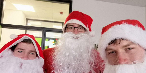 Drei als Weihnachtsmann/Nikolaus verkleidete Personen im Sofazimmer.